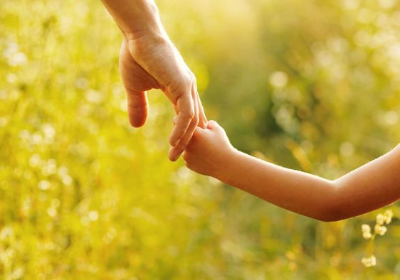 A parent holds the hand of a child.