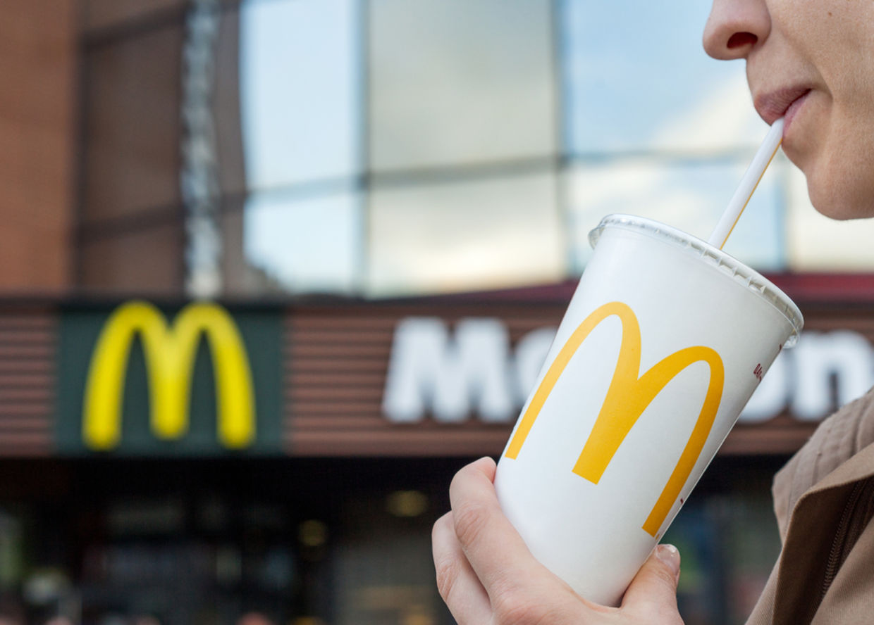 Woman drinks a drink in the background of the McDonald's restaurant Woman drinks a drink in the background of the McDonald's restaurant