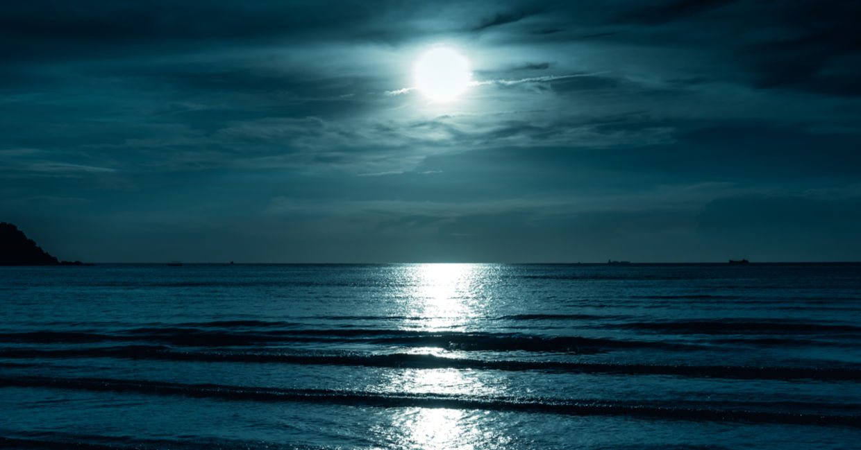 A full moon shines across the sea, creating a reflection on the water that looks like a road. A full moon shines across the sea, creating a reflection on the water that looks like a road.