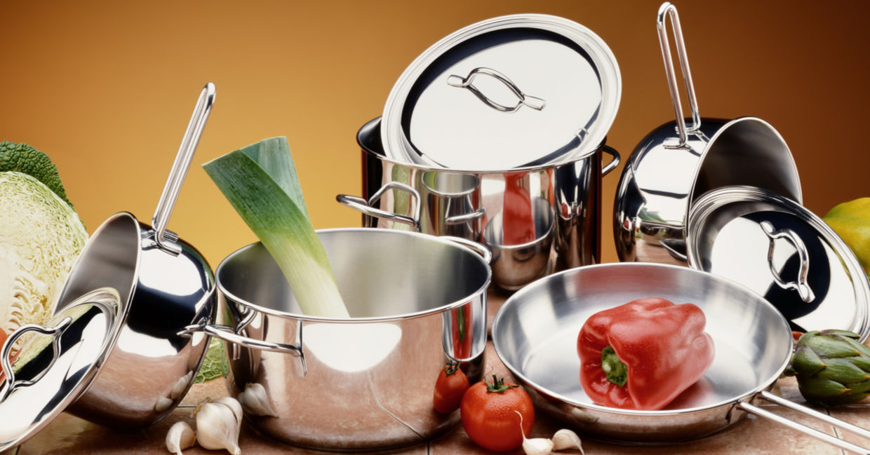 A selection of stainless steel pots and pans with healthy, raw ingredients. A selection of stainless steel pots and pans with healthy, raw ingredients.