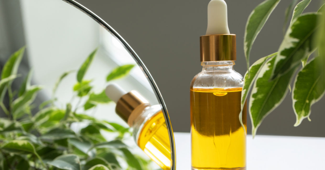 A bottle of vitamin E oil, nourishing for skin and hair, is beside a makeup mirror. A bottle of vitamin E oil, nourishing for skin and hair, is beside a makeup mirror.