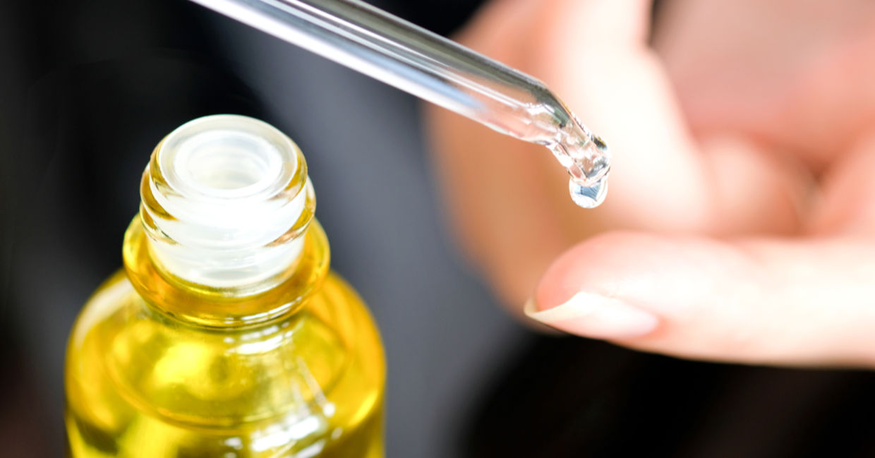 A woman places a drop of healing vitamin E oil on her skin. A woman places a drop of healing vitamin E oil on her skin.