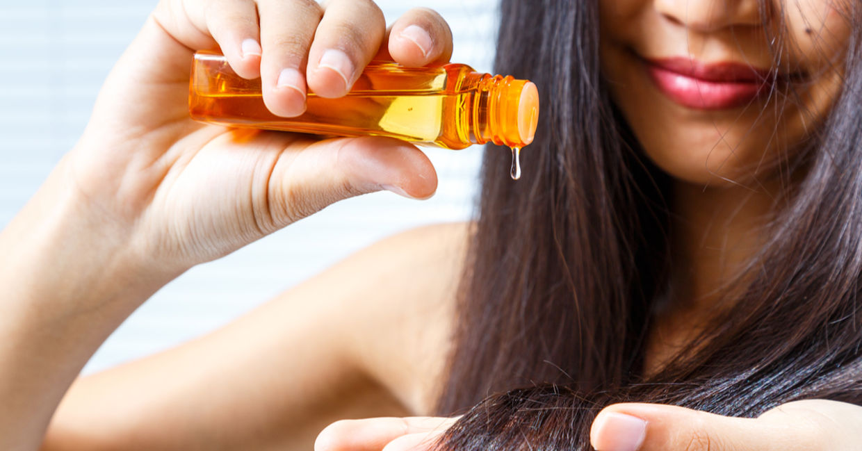 A woman treats her split ends with drops of healing and nourishing vitamin E oil. A woman treats her split ends with drops of healing and nourishing vitamin E oil.