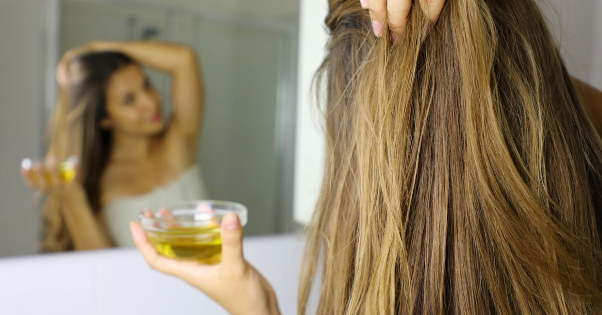 To revitalize her hair, a woman rubs vitamin E and coconut oil into her scalp. To revitalize her hair, a woman rubs vitamin E and coconut oil into her scalp.
