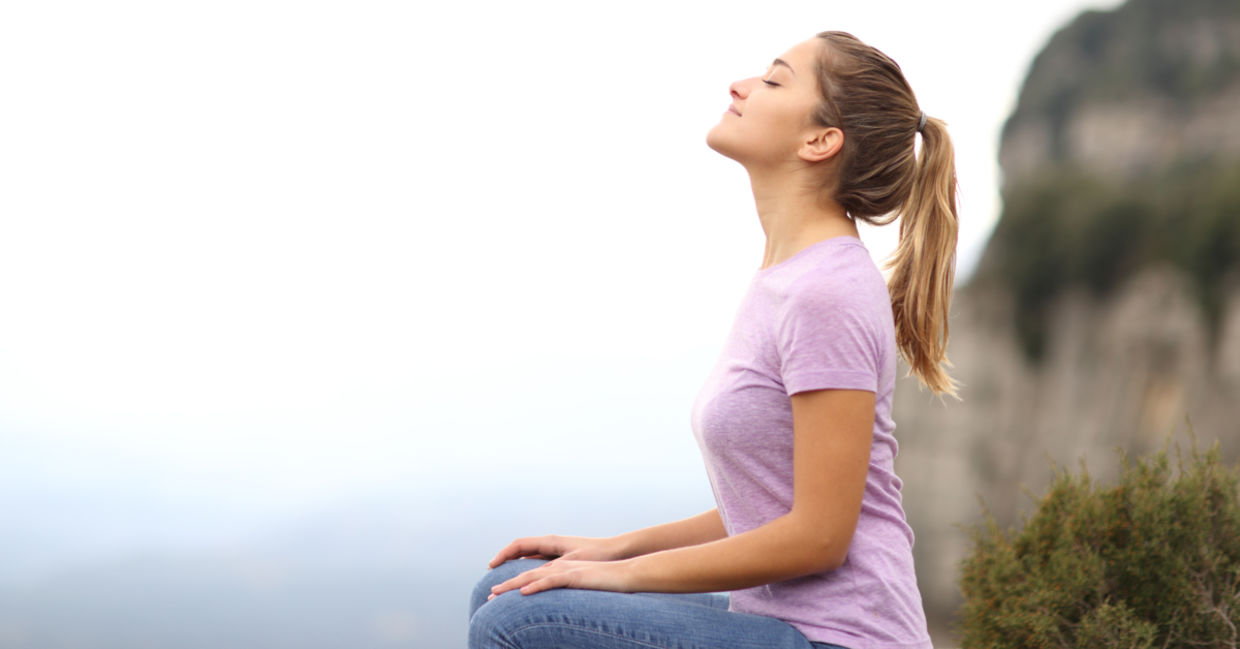 A woman focuses on her breath as she practices a mindful meditation outside. A woman focuses on her breath as she practices a mindful meditation outside.