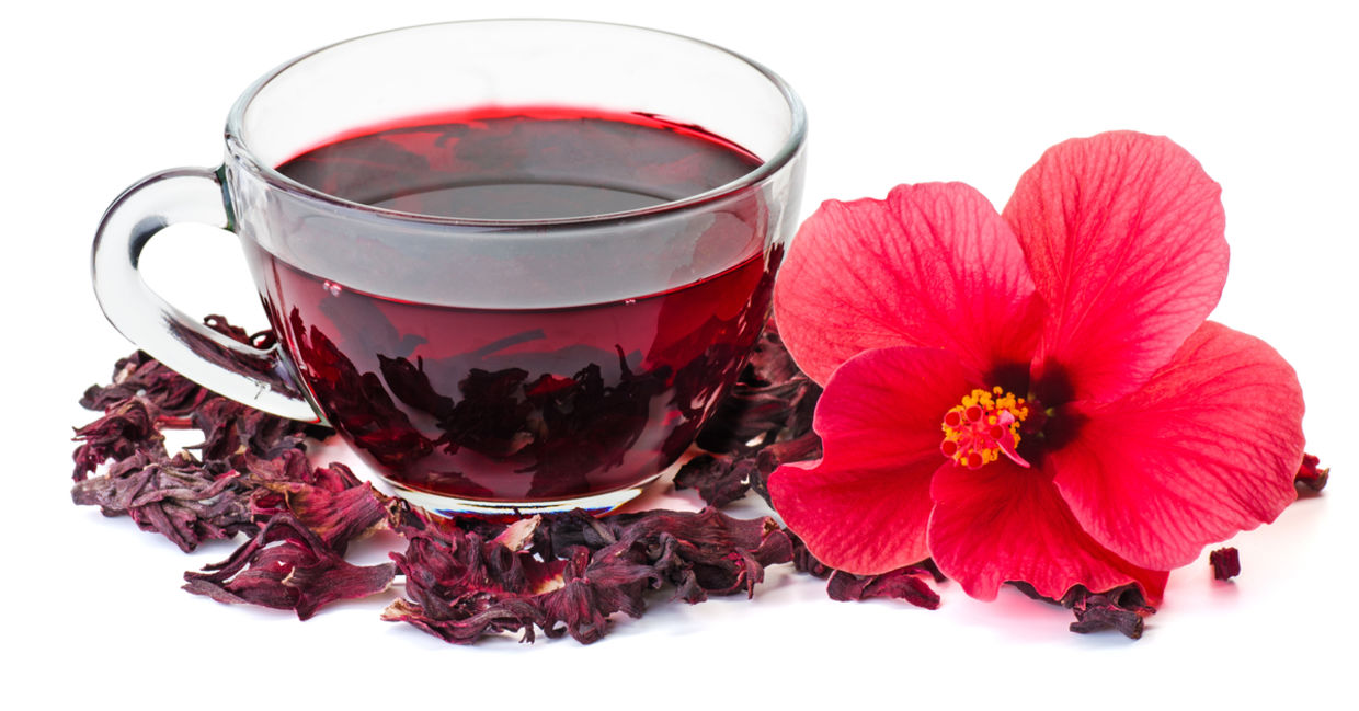 A hibiscus flower beside a cup of healthy hibiscus tea. A hibiscus flower beside a cup of healthy hibiscus tea.