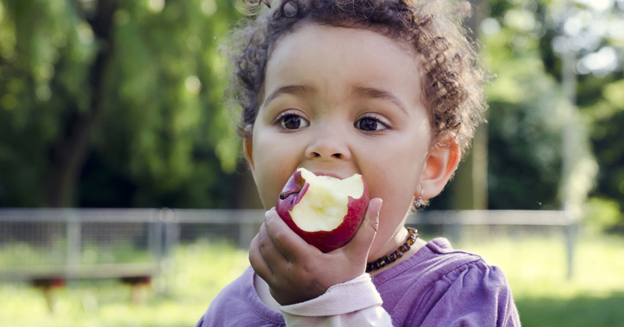 A young girl is enjoying eating an apple. A young girl is enjoying eating an apple.