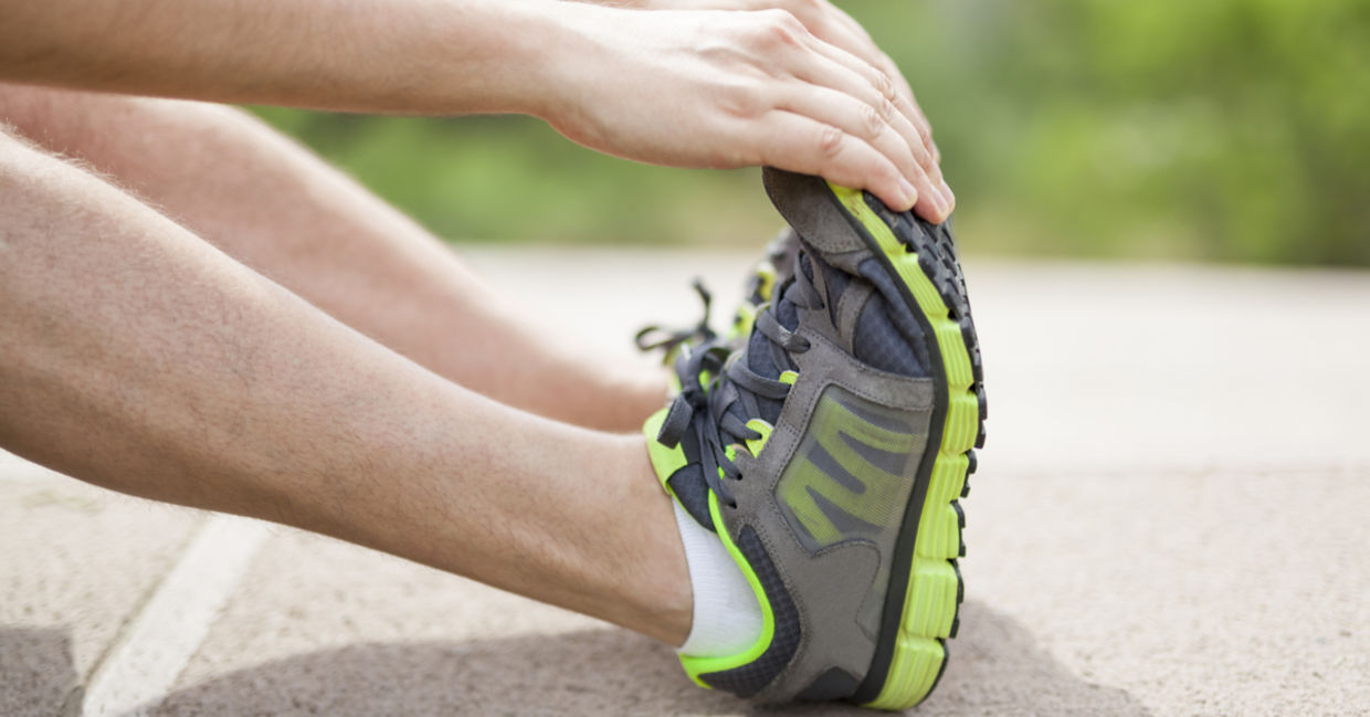 An athlete doing foot stretches to prevent injuries An athlete doing foot stretches to prevent injuries