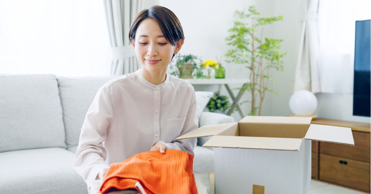 A woman stores seasonal clothes in a cardboard box. A woman stores seasonal clothes in a cardboard box.