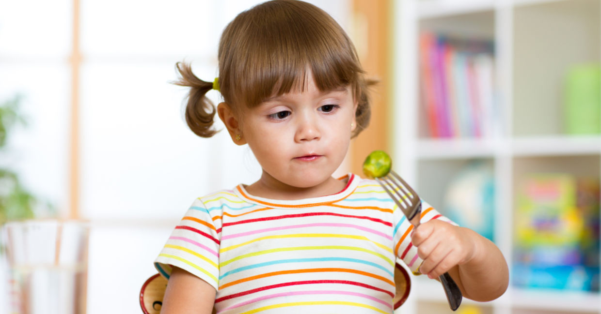 A little girl eats brussels sprouts. A little girl eats brussels sprouts.