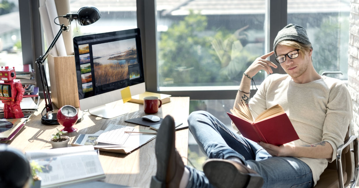 Man engrossed in reading a book at his workstation. Man engrossed in reading a book at his workstation.