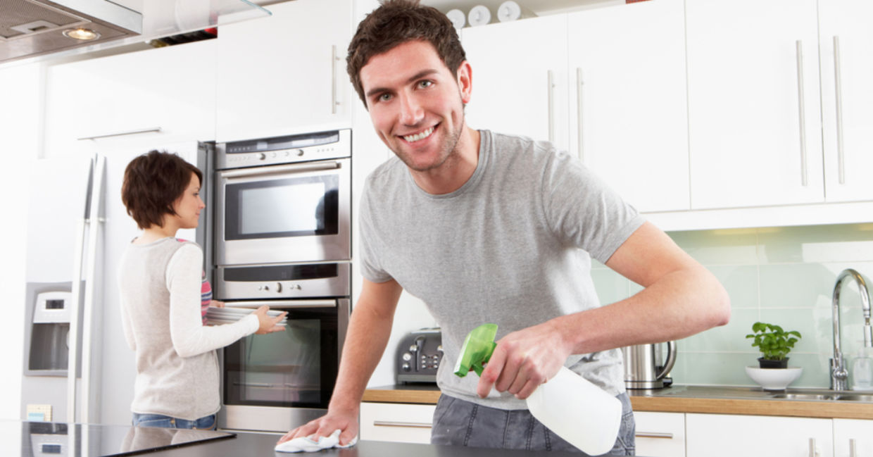 A man cleans his kitchen with a citric acid spray. A man cleans his kitchen with a citric acid spray.
