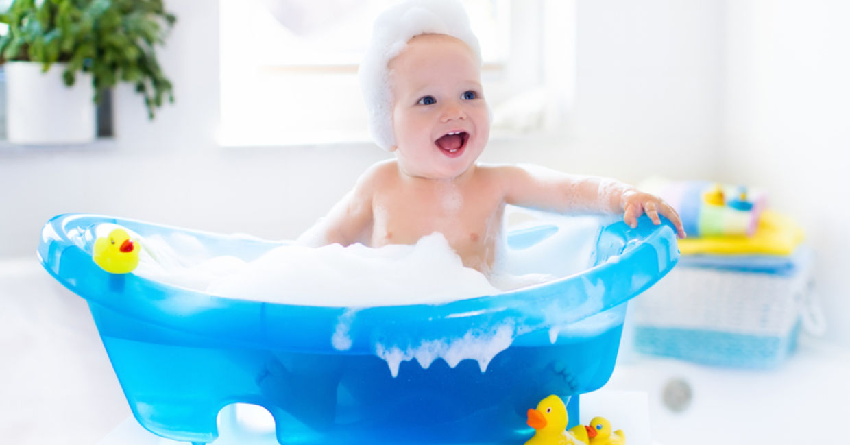 A baby with suds laughs in the tub. A baby with suds laughs in the tub.