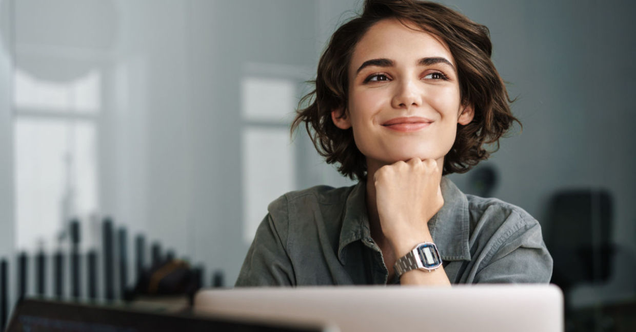 A smiling woman working on her laptop. A smiling woman working on her laptop.