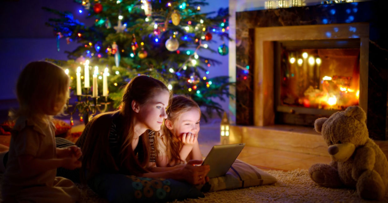 A young mom and her children watch a show at Christmas on a tablet. A young mom and her children watch a show at Christmas on a tablet.
