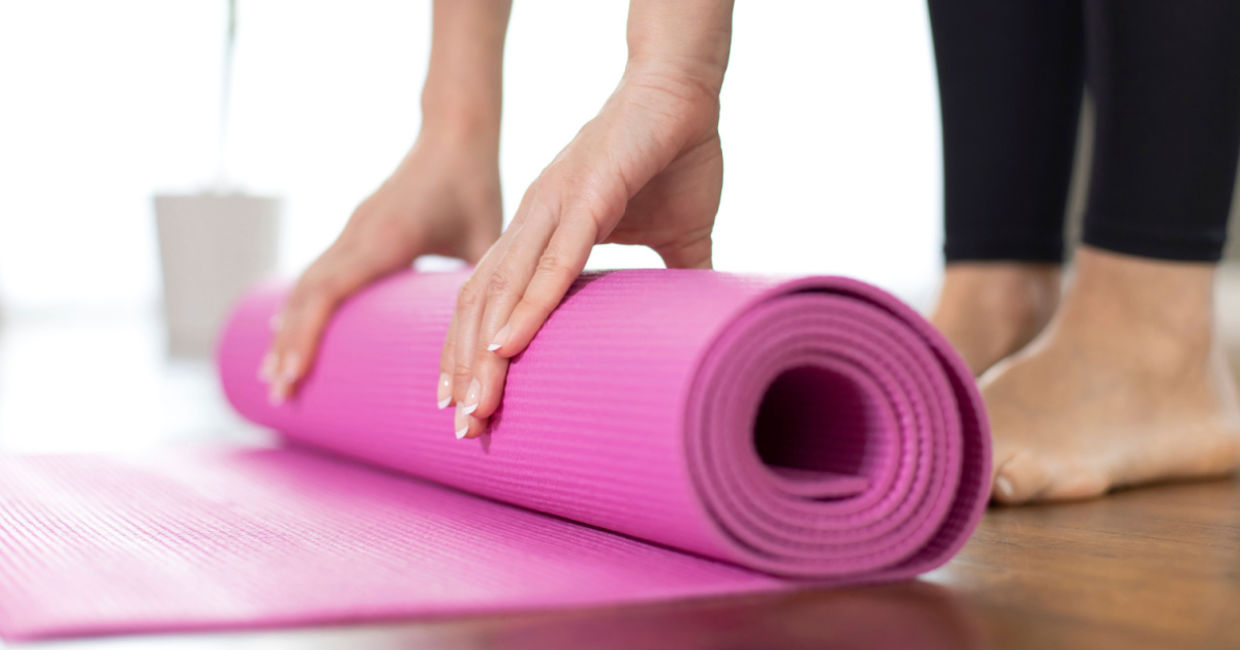 Woman unrolling her yoga mat. Woman unrolling her yoga mat.