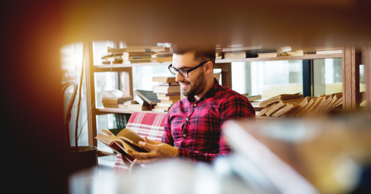 Young man reading a book at a modern library. Young man reading a book at a modern library.