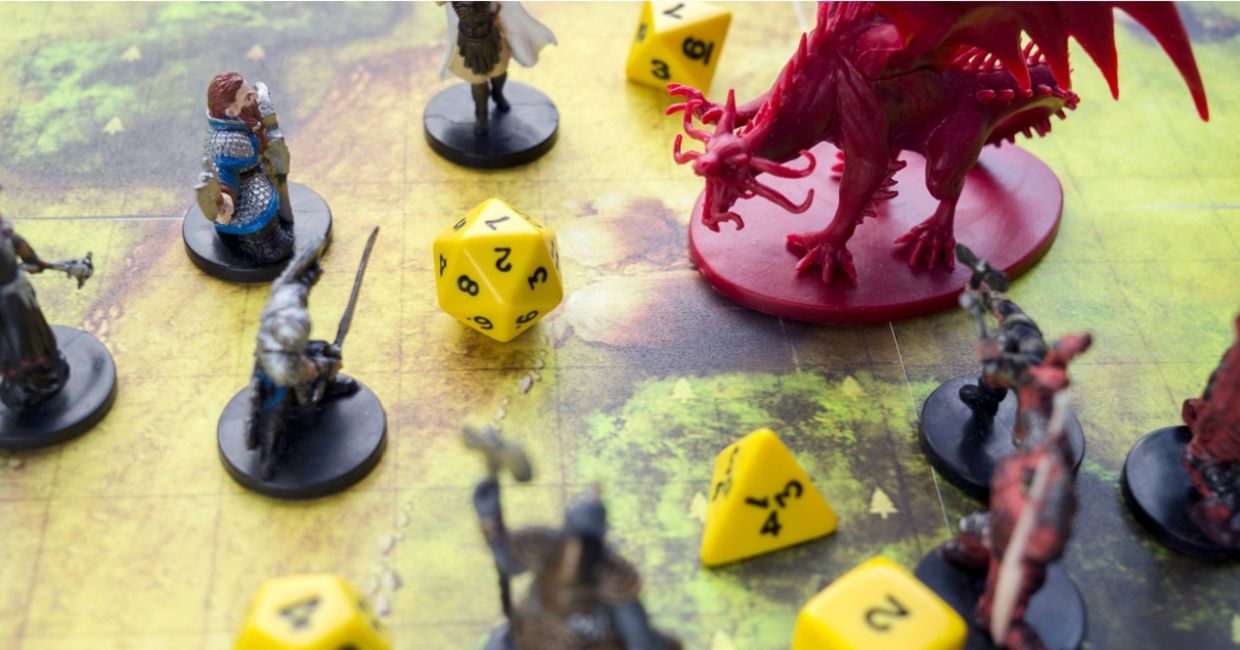 Playing Dungeons and Dragons on a board game map with a figure of a dragon, game characters and dice. Playing Dungeons and Dragons on a board game map with a figure of a dragon, game characters and dice.