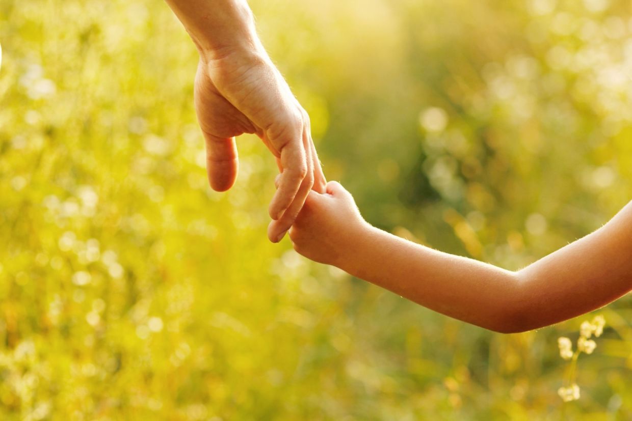 A parent holds the hand of a child.